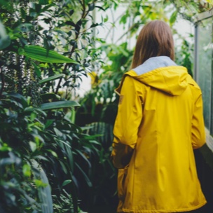 girl wearing a yellow jacket looking at leaves